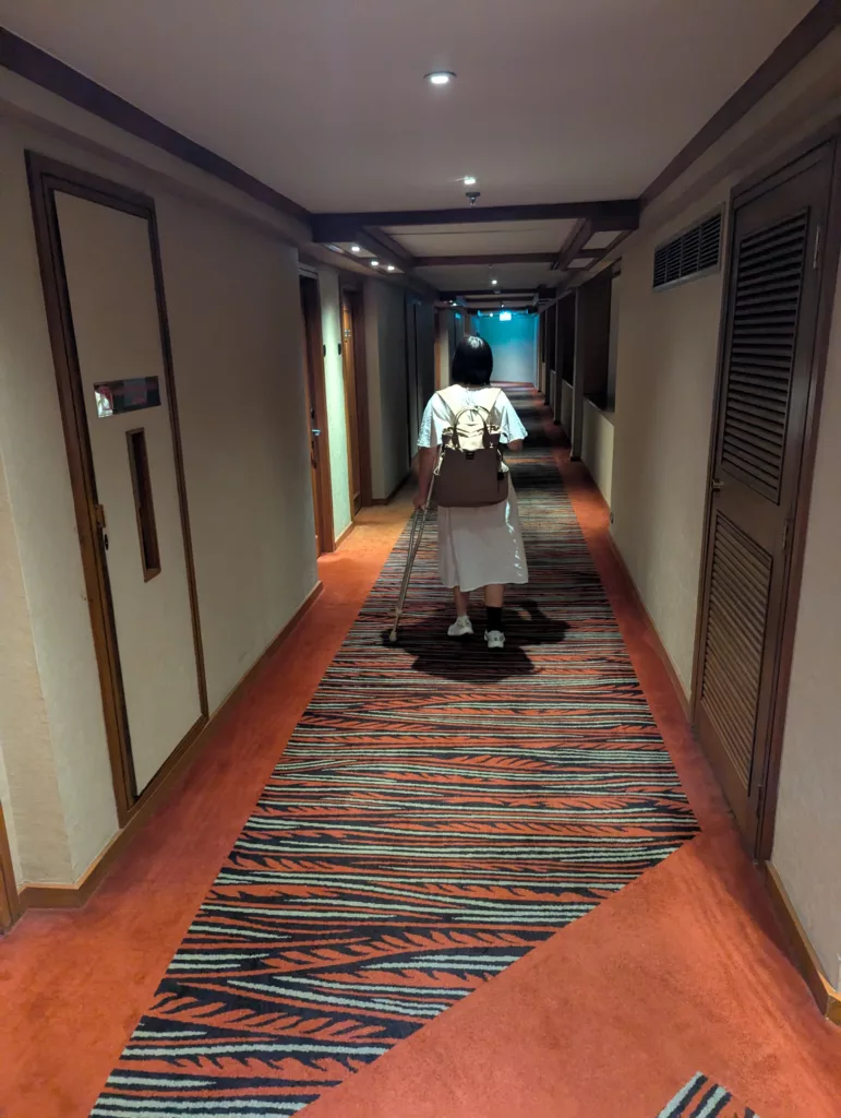 Sachi in hotel corridor with crutch.